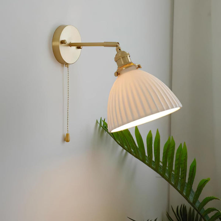 Vägglampa i keramik med plissering i mässing