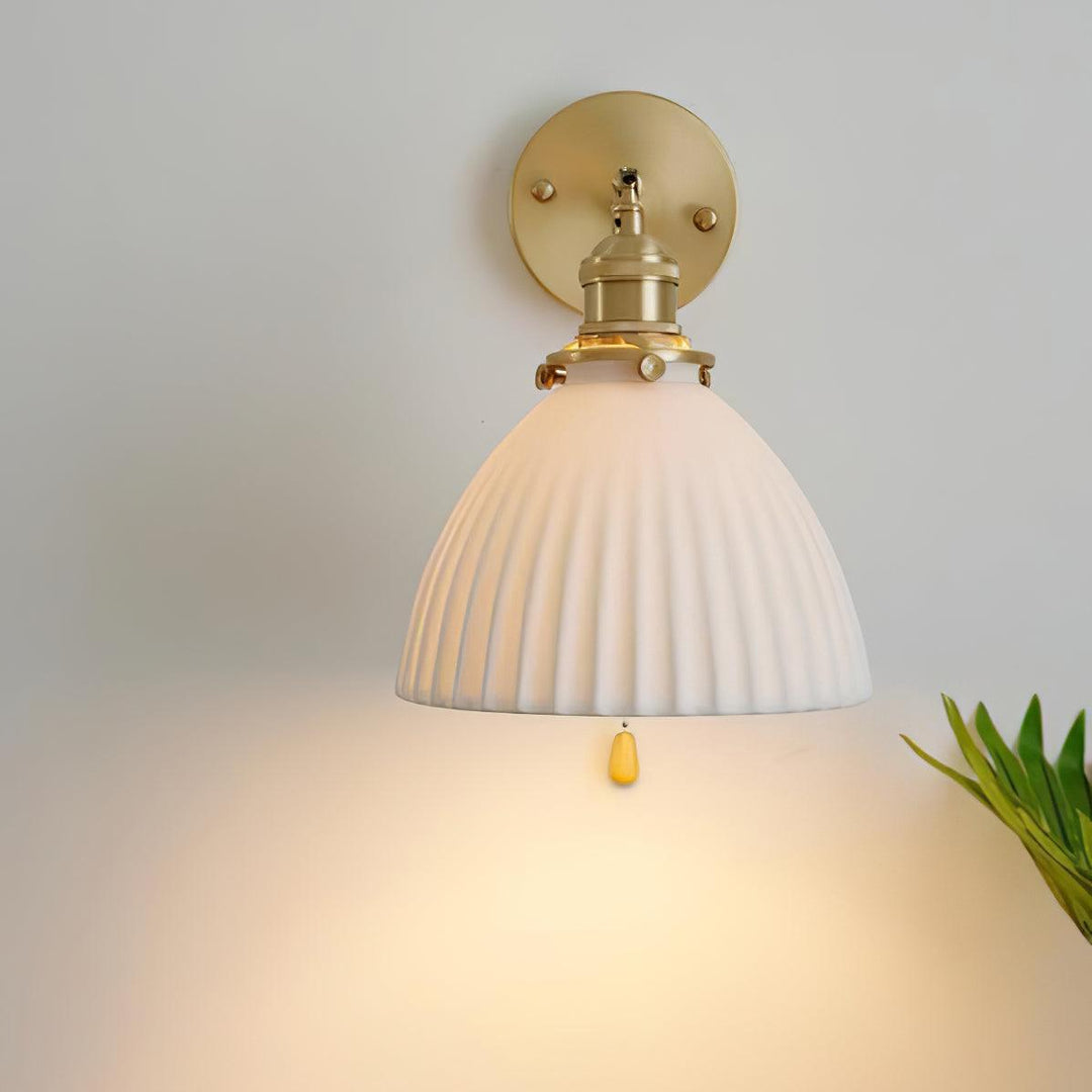Vägglampa i keramik med plissering i mässing